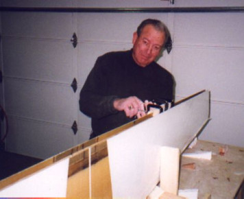 Made jig to hold horizontal stabilizer verticle. Filled hinge holes with clay, Q-cell radiused the shear web and applied 2 layer laminates to upper and lower horizontal stabilizer panels and shear web. Cut 14 strips of BID for application to the leading edge of the horizontal stabilizer. Repaired bubble in rear shear laminate (photo)