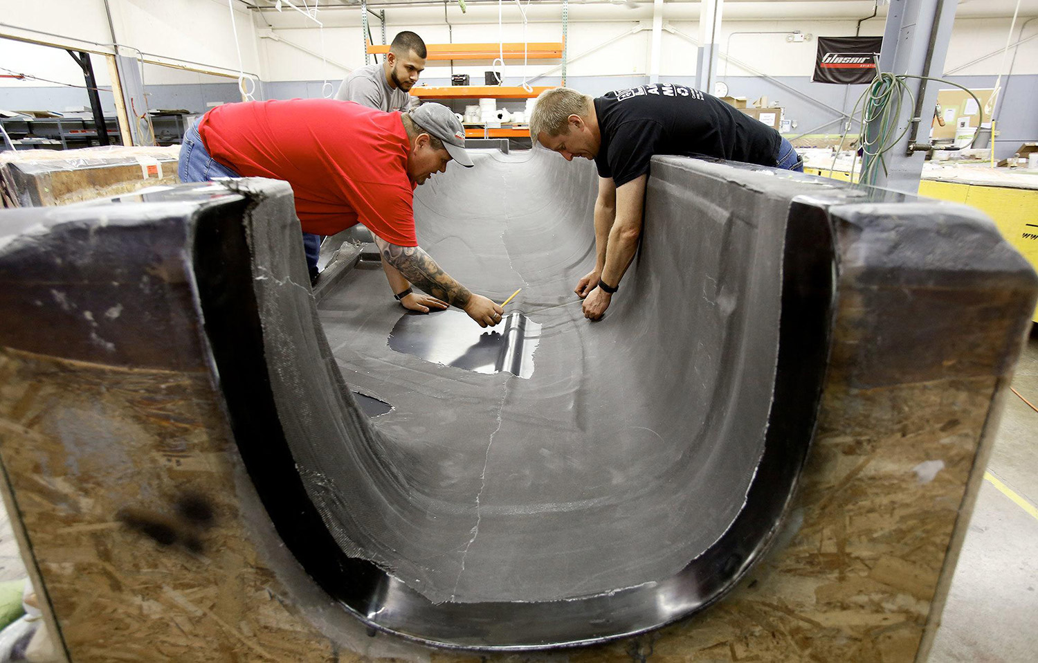 Glasair employees Jeramy Olson, Omar Alvarez and Ken Andreason (right) talk about seat belt attachment points as they measure the right fuselage of a carbon fiber composite body for a new Merlin airplane. Photo: Andy Bronson / The Herald